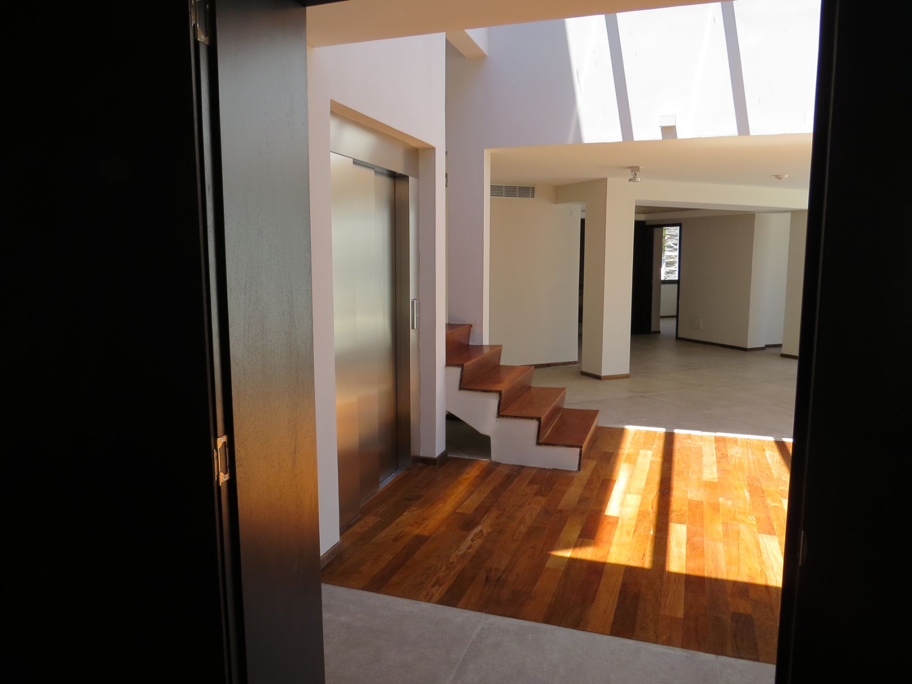 La fotografía fue tomada desde dentro de uno de los consultorios, en la misma se aprecia el recibidor principal de la clínica de punta del este, con la entrada a los consultorios de fondo.